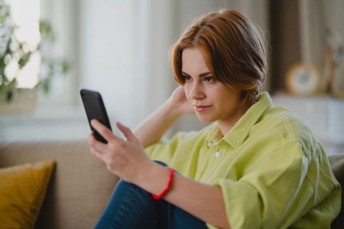 A woman on her sofa looking at her phone