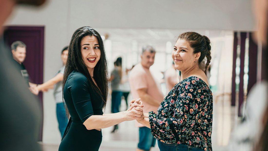 Two dance partners holding hands and laughing mid-lesson