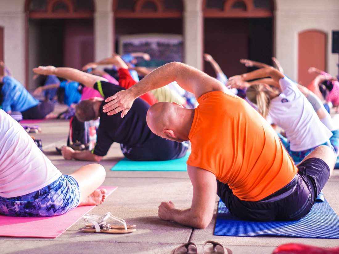 A yoga class mid flow, mats in rows, warm morning light